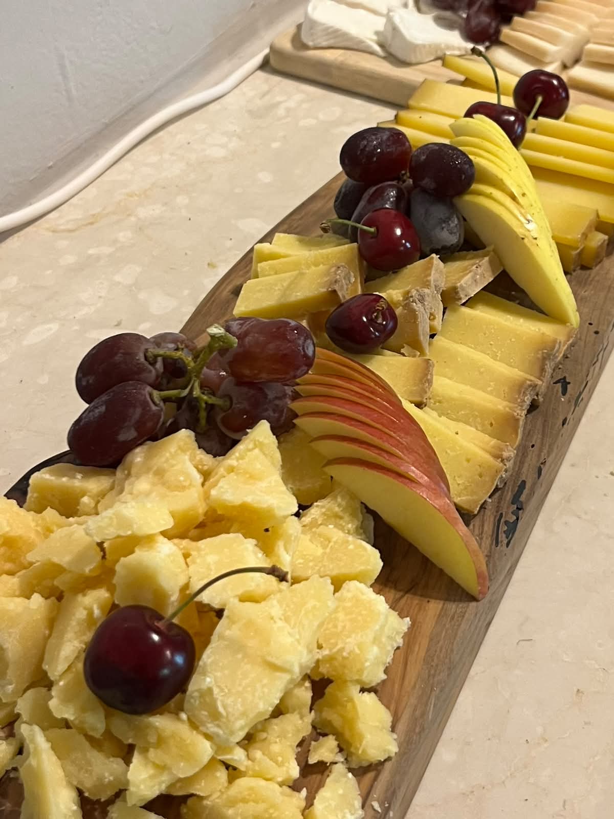 Wooden board of local mountain cheeses with grapes, apple and cherries