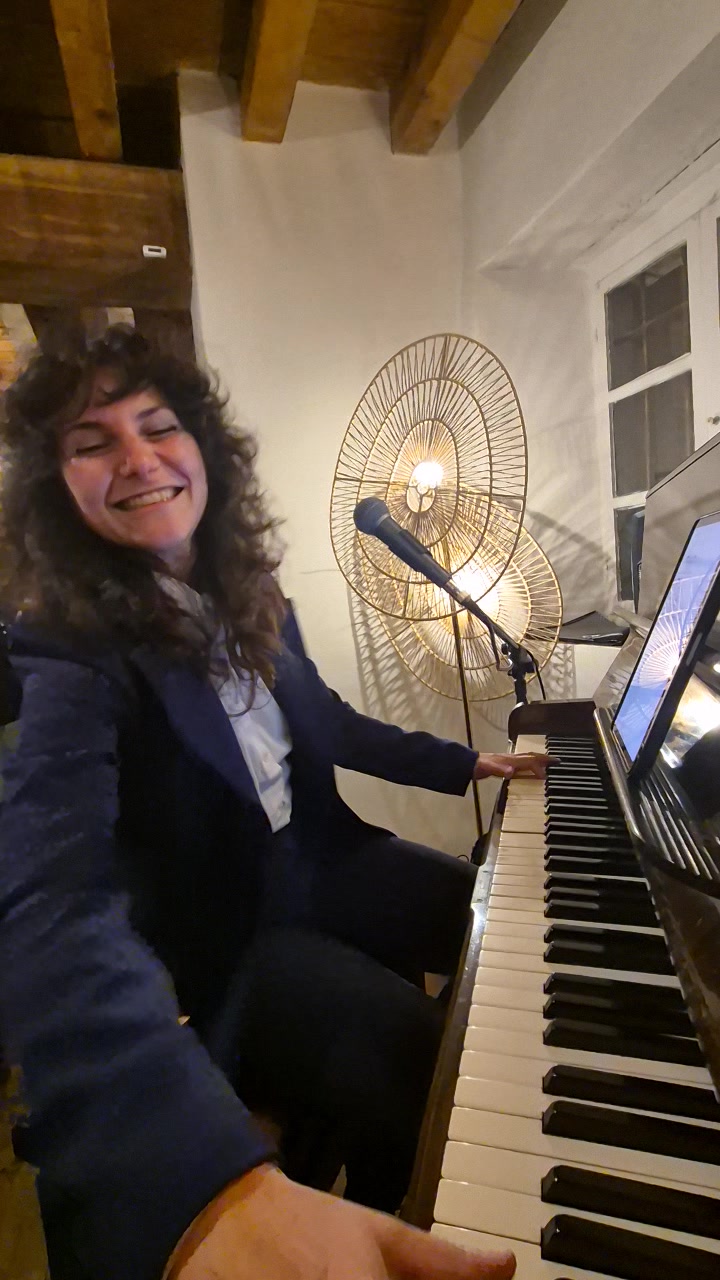 Nicole smiling joyfully at the piano during a live performance