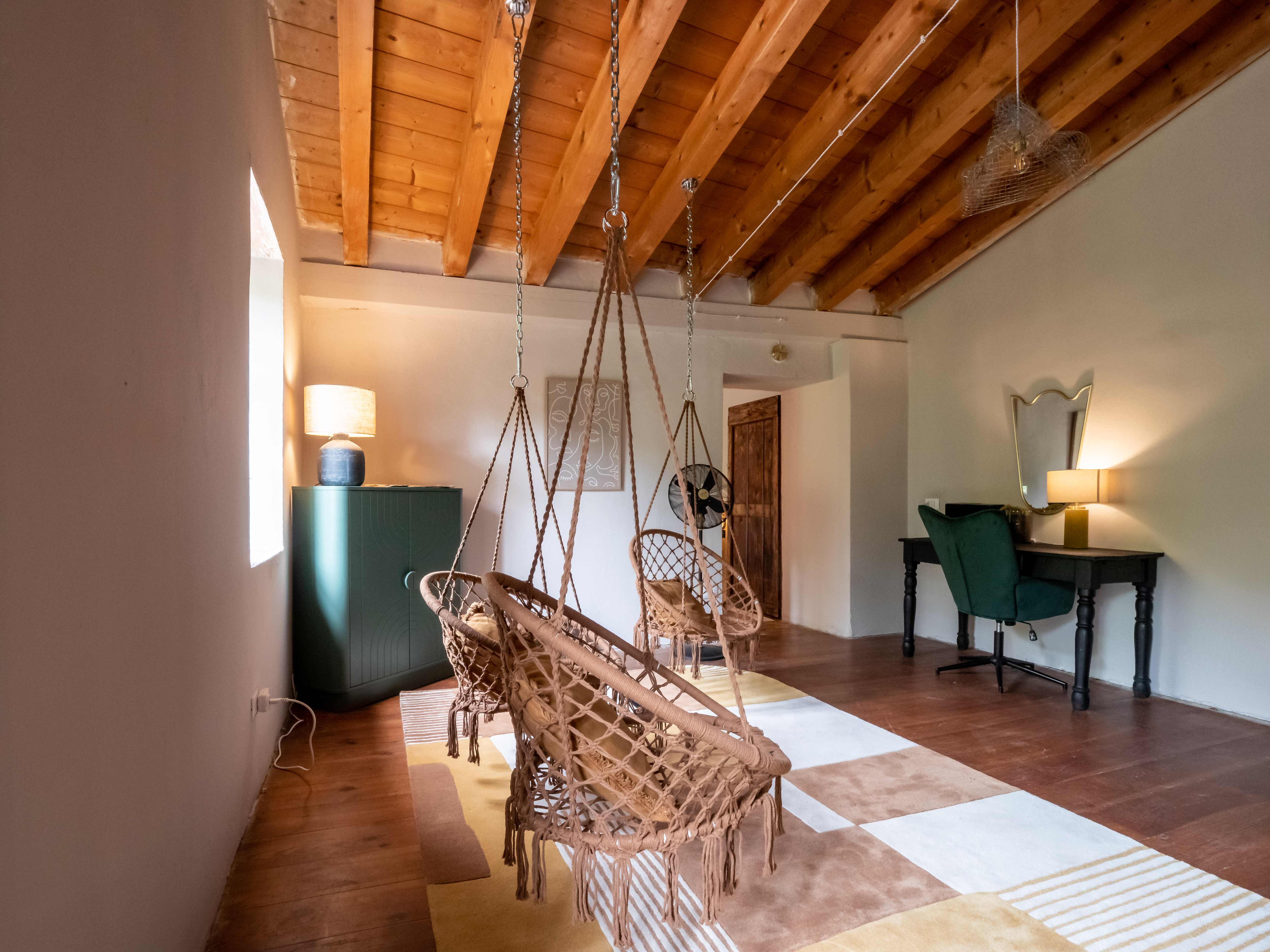 Loft lounge with multiple macrame hammock chairs under exposed wooden beams