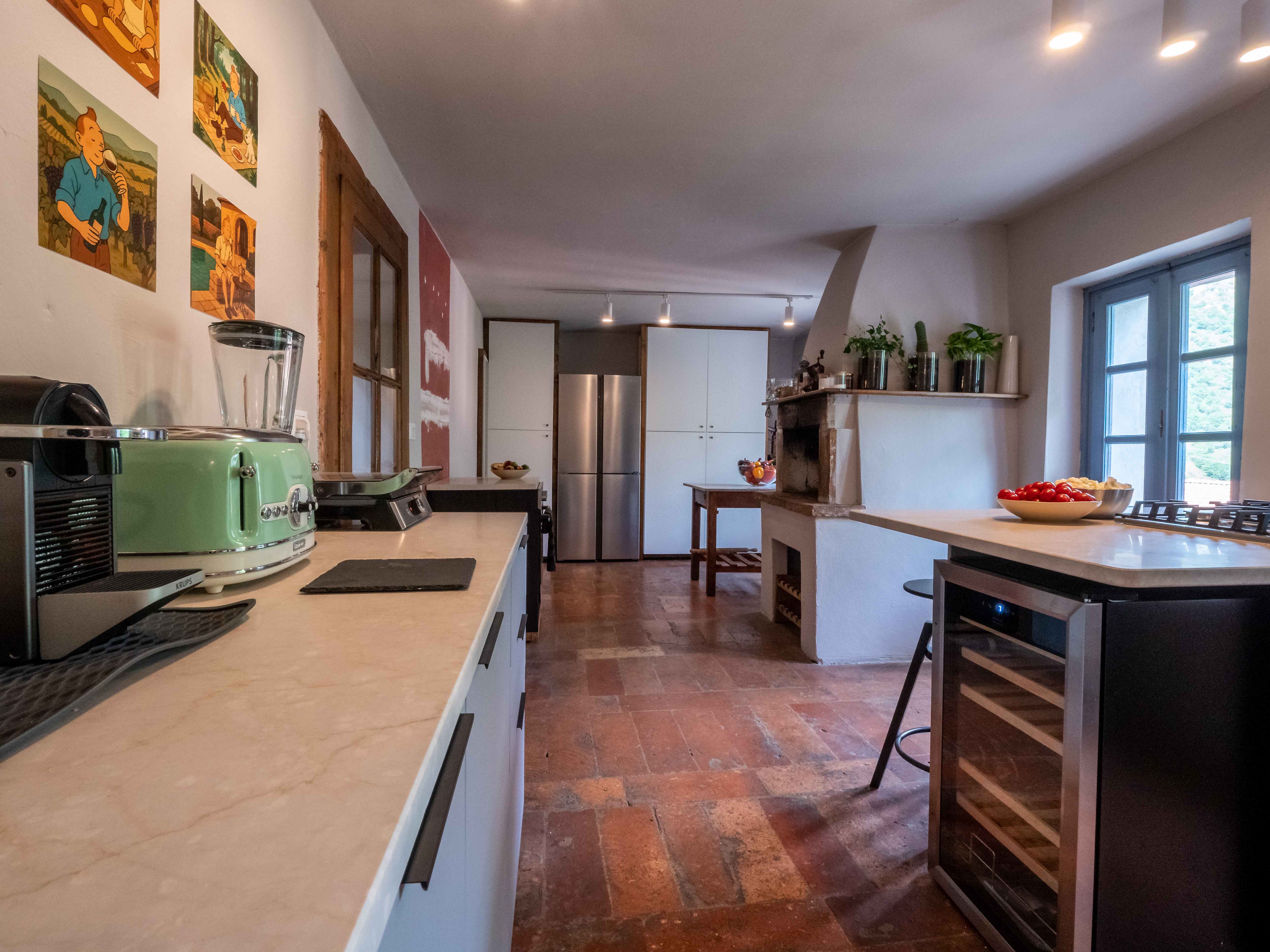 Modern kitchen with stainless steel appliances and historic fireplace