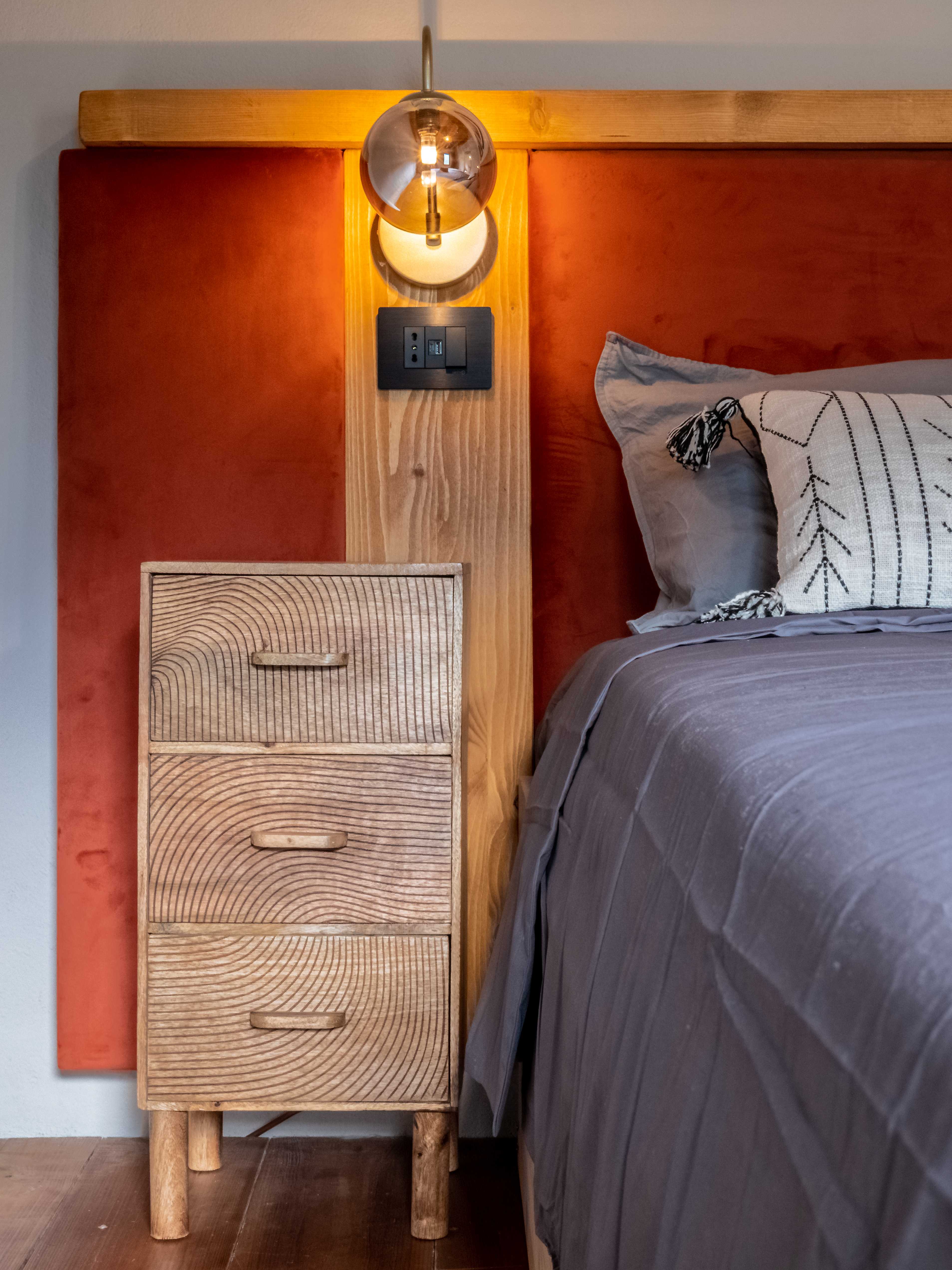 Handcrafted wooden bedside table with wave pattern and terracotta headboard
