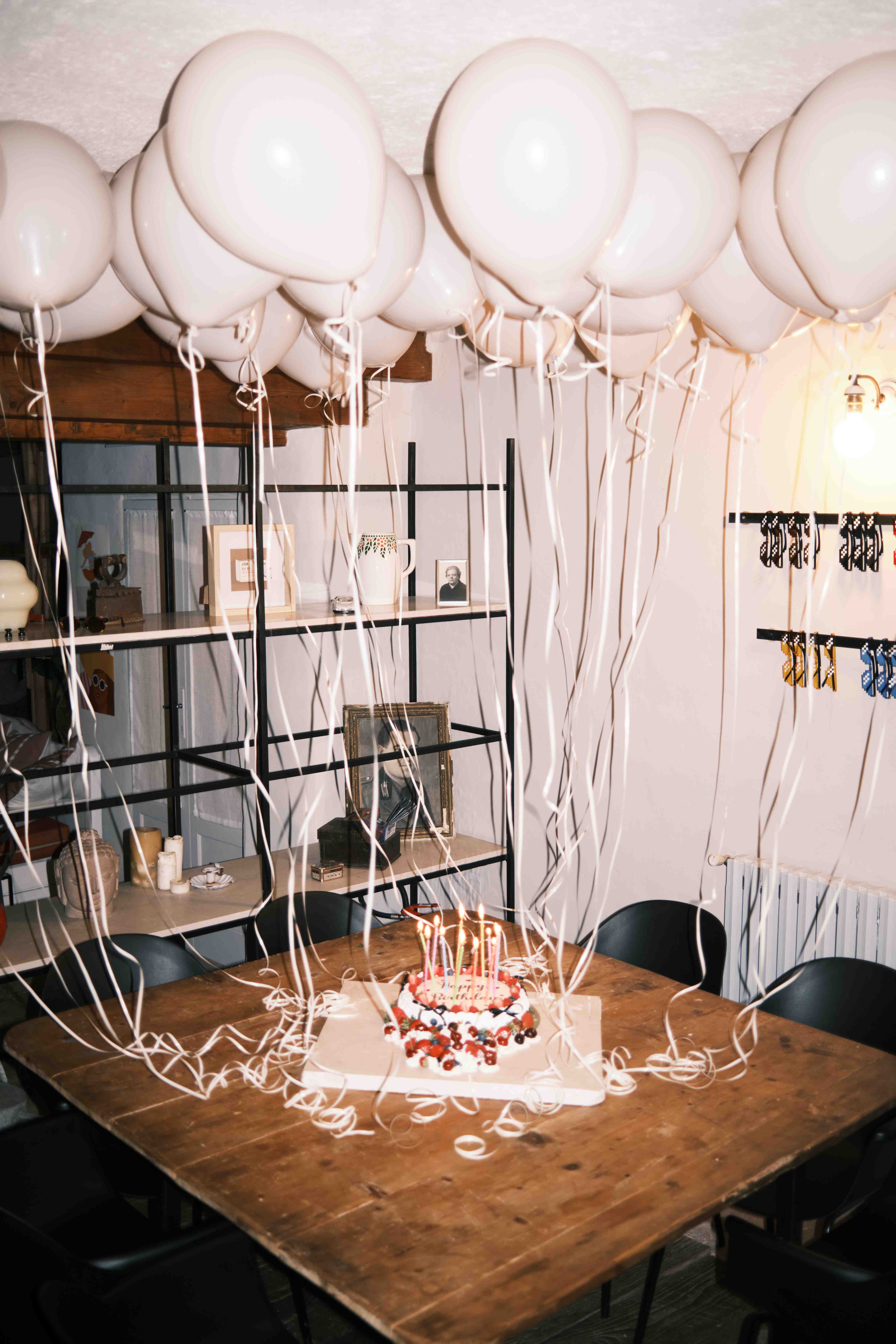 Birthday cake beneath a canopy of white balloons
