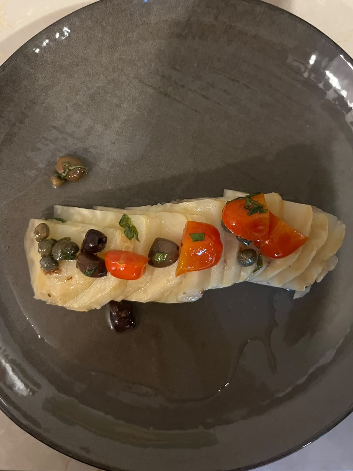 Plated fish fillet with cherry tomatoes, olives and capers